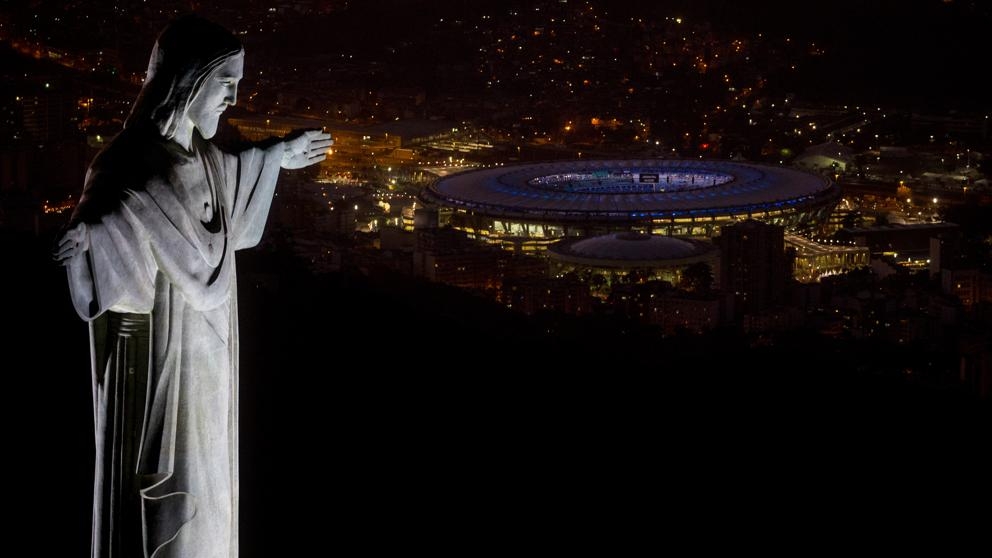 La monumental estatua del Cristo Redentor, de 30 metros de altura, en primer plano; al fondo, Maracaná iluminado por el ensayo de la ceremonia inaugural Foto: Chris Mcgrath / Getty