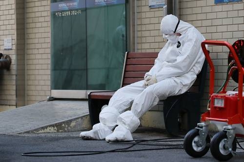 Un trabajador de salud descansa mientras espera la llegada de ambulancias con pacientes contagiados por el coronavirus en un hospital de Daegu, Corea del Sur, donde se reportan siete muertos y 764 infectados.Foto Afp