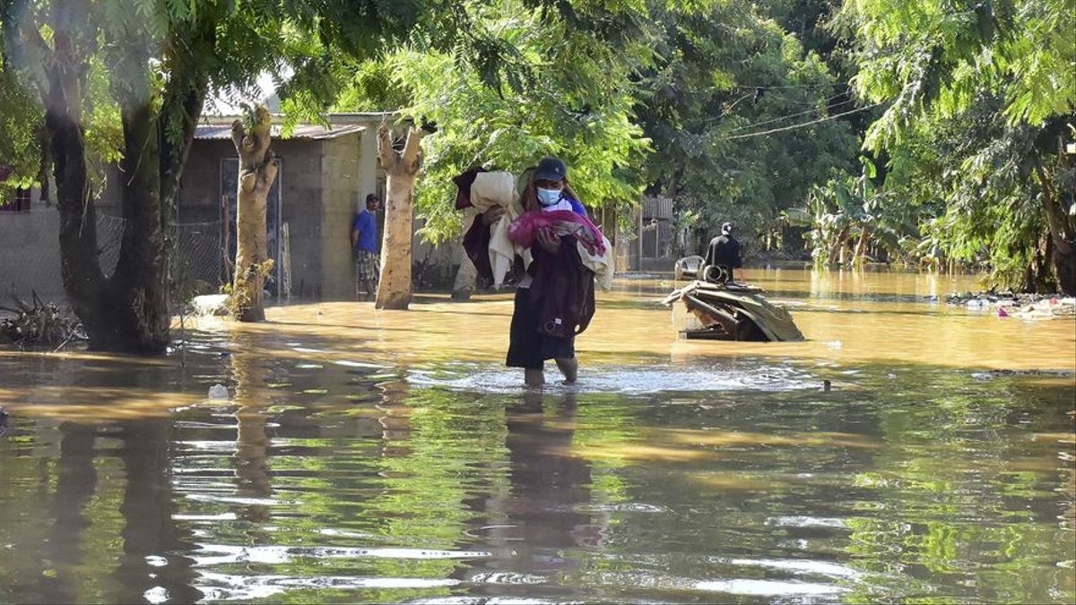 Un hombre camina con sus pertenencias en una de las zonas inundadas durante la temporada de huracanes en Honduras.