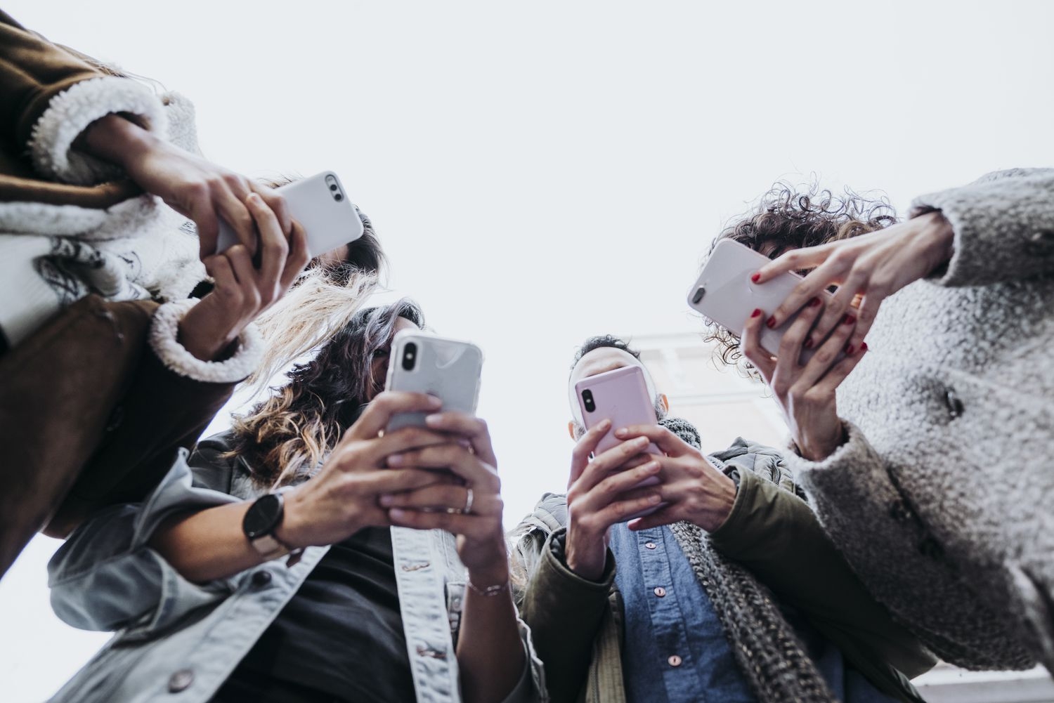 Cuatro amigos usan sus teléfonos móviles en la calle.KARRASTOCK / Getty Images